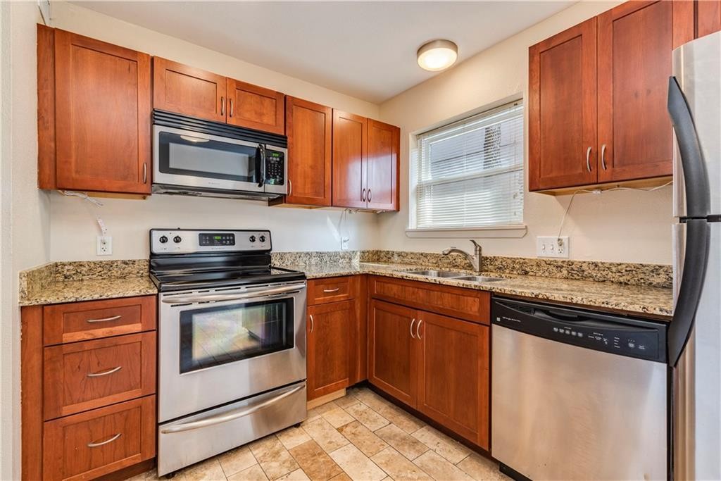 a kitchen with stainless steel appliances granite countertop a stove microwave and sink