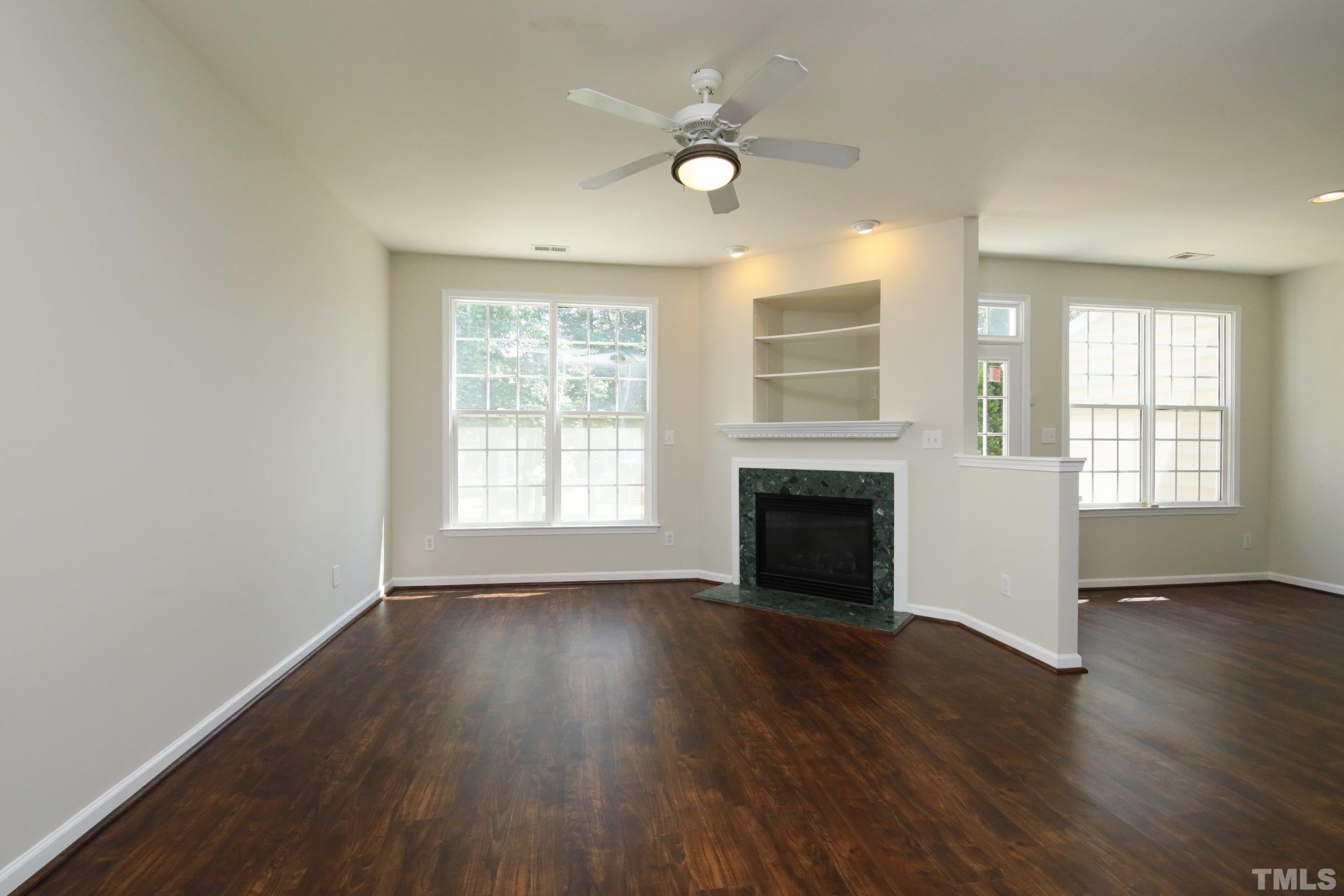 5633 Slide Rock Lane Raleigh, NC 27613 - Photo 5 of 32 an empty room with wooden floor fireplace and windows