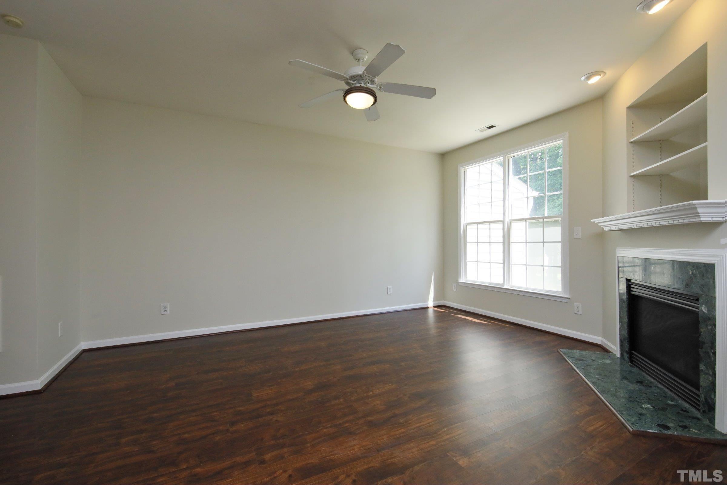5633 Slide Rock Lane Raleigh, NC 27613 - Photo 6 of 32 an empty room with wooden floor fireplace and windows