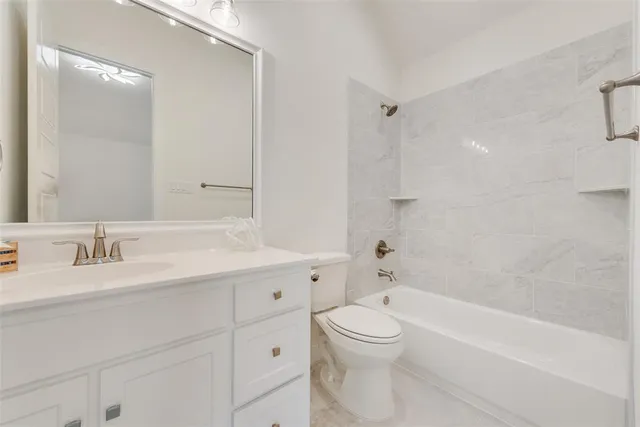 a bathroom with a bathtub shower sink vanity mirror and toilet