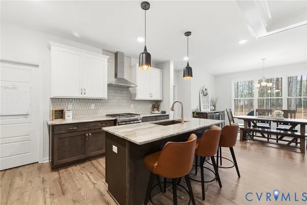 a kitchen with stainless steel appliances granite countertop a stove a sink a dining table and chairs with wooden floor