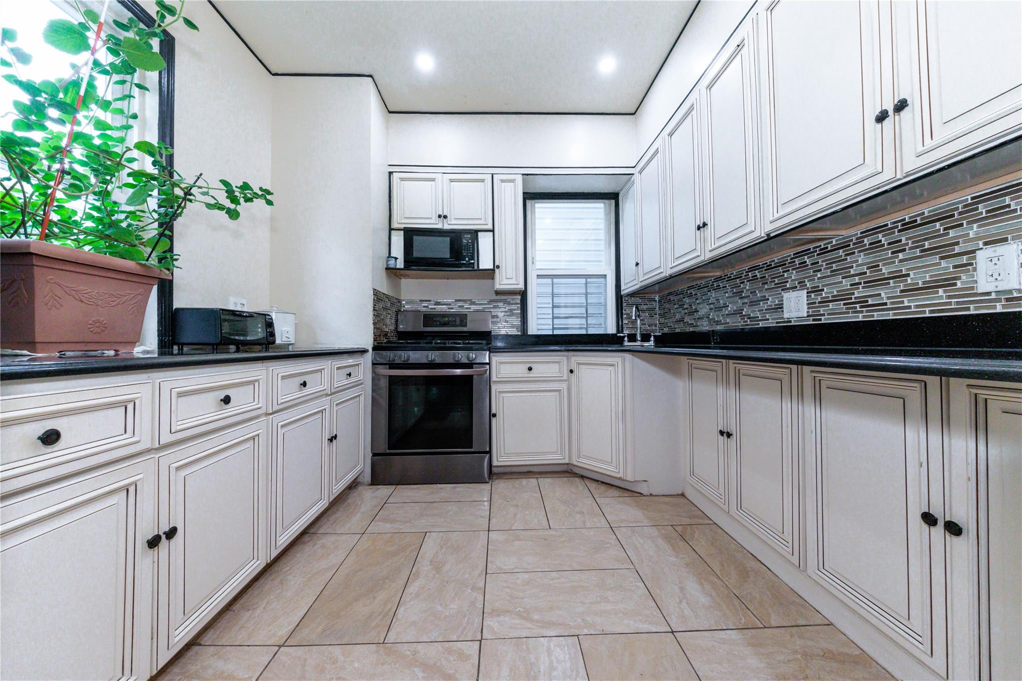 85-21 80th Street Queens, NY 11421 - Photo 14 of 39 a kitchen with white cabinets and appliances