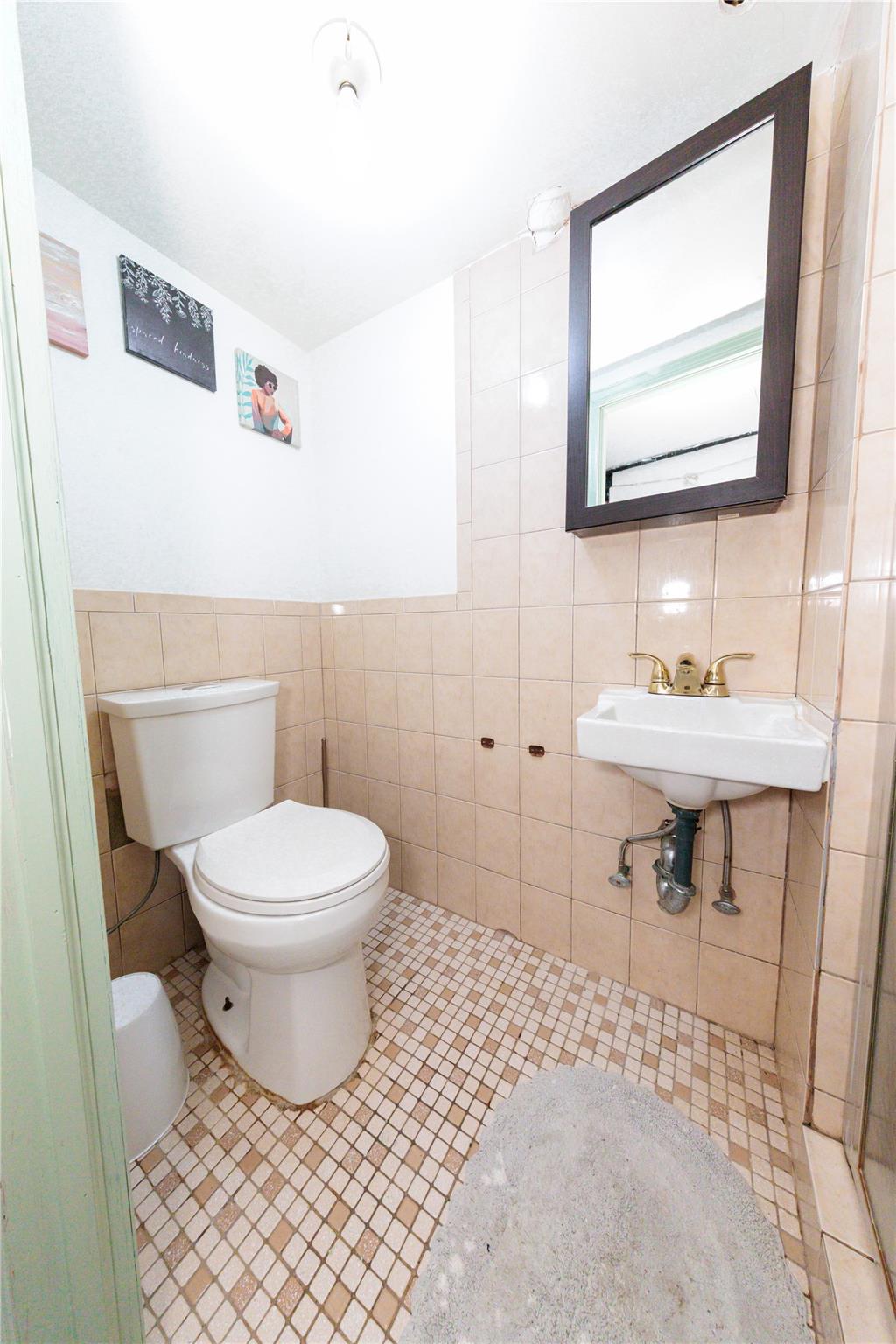 85-21 80th Street Queens, NY 11421 - Photo 33 of 39 a bathroom with a toilet a sink and mirror