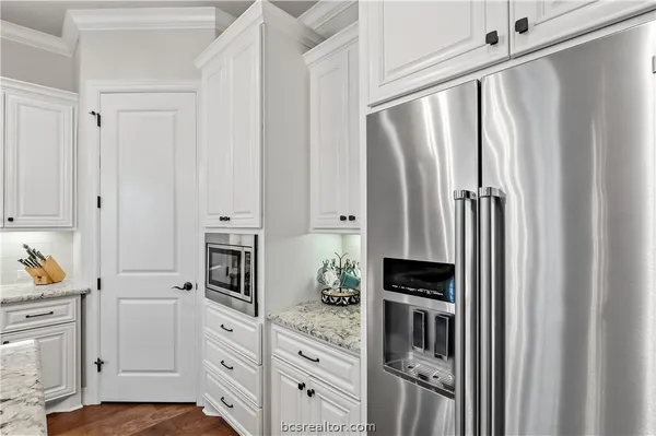 a kitchen with stainless steel appliances a refrigerator and white cabinets