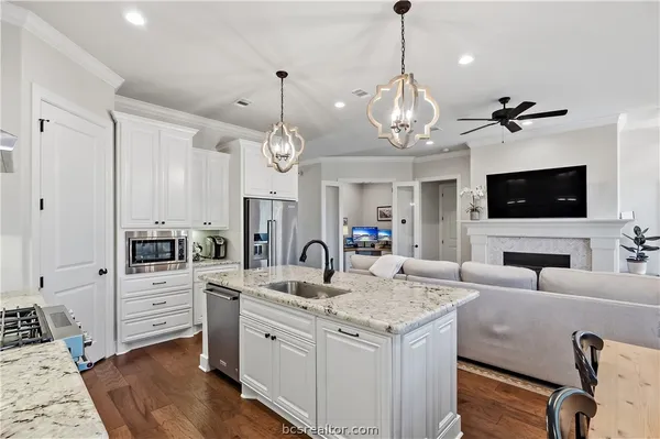 a view of living room kitchen with granite countertop stainless steel appliances and fireplace
