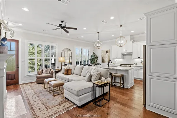 a living room with furniture kitchen view and a wooden floor