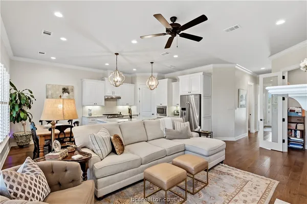 a living room with furniture kitchen view and a wooden floor