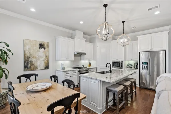 a kitchen with stainless steel appliances granite countertop a kitchen island a stove a table and chairs