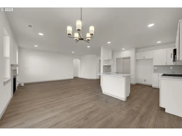 a view of an empty room and kitchen with furniture wooden floor