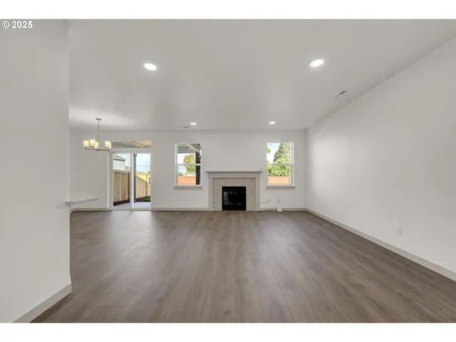 a view of an empty room with a fireplace and window