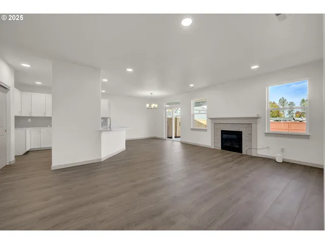 a view of an empty room with wooden floor a fireplace