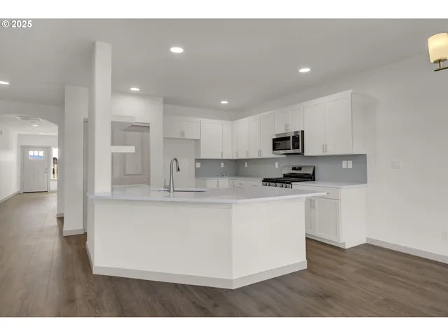 a kitchen with stainless steel appliances granite countertop a stove a sink a refrigerator and a microwave