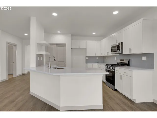 a kitchen with stainless steel appliances kitchen island a sink dishwasher a refrigerator and a stove with wooden floor