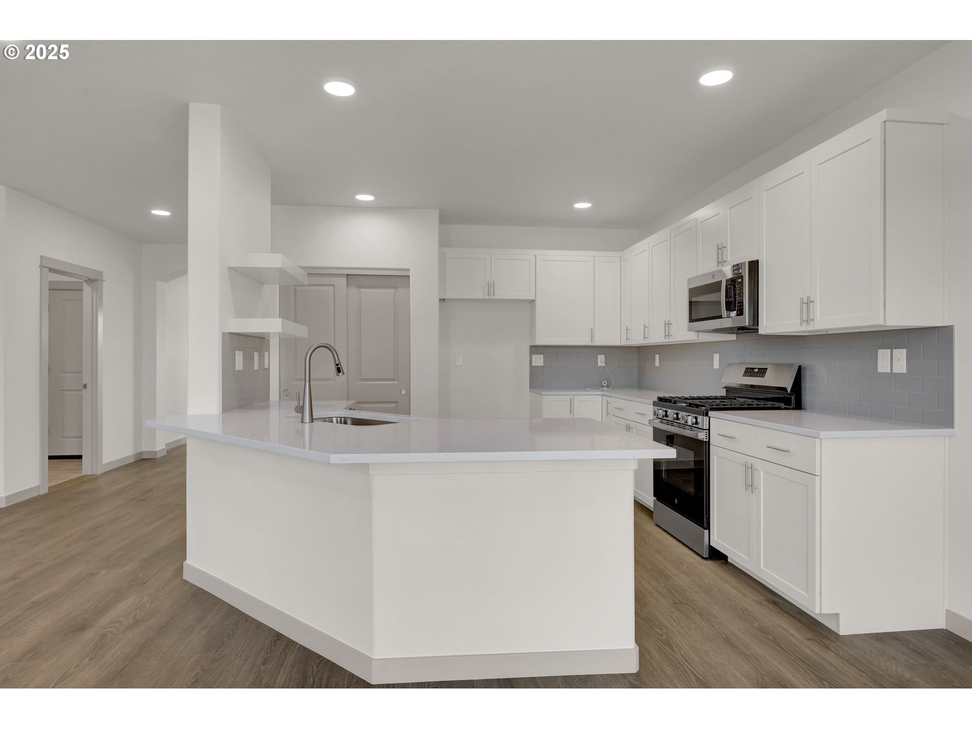 5645 Magnificence Way Eugene, OR 97402 - Photo 6 of 38 a kitchen with stainless steel appliances kitchen island a sink dishwasher a refrigerator and a stove with wooden floor