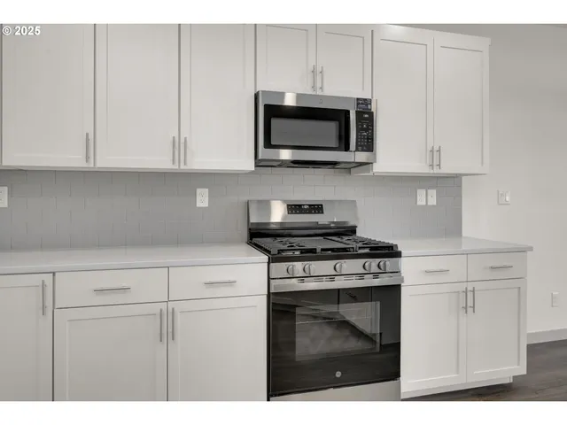 a kitchen with white cabinets and stainless steel appliances