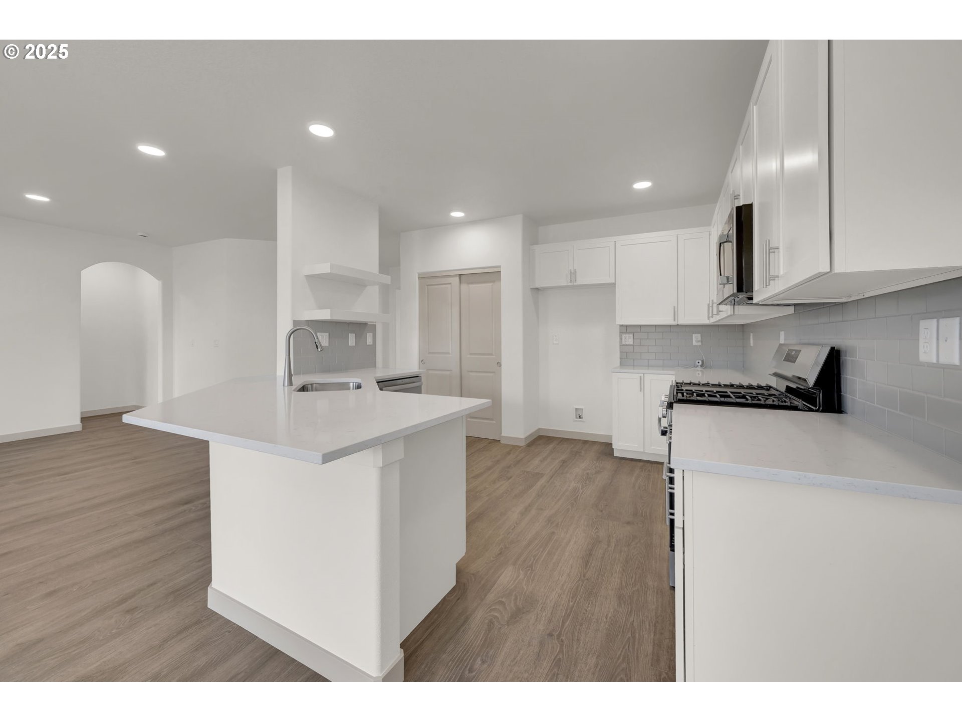 5645 Magnificence Way Eugene, OR 97402 - Photo 10 of 38 a kitchen with stainless steel appliances kitchen island granite countertop a stove a sink a refrigerator and white cabinets with wooden floor