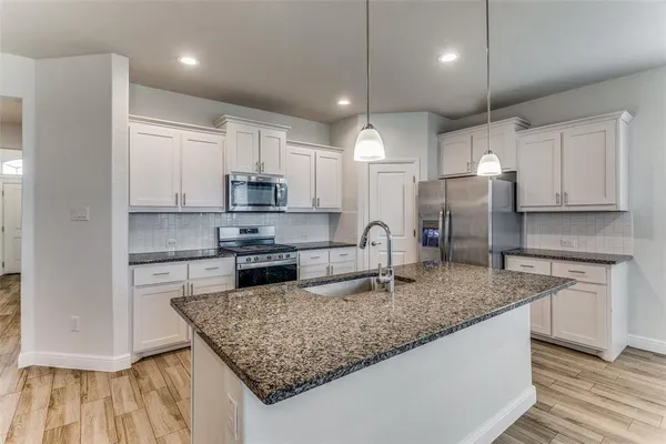 a kitchen with stainless steel appliances granite countertop a sink refrigerator and microwave