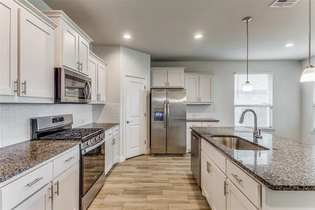 a kitchen with stainless steel appliances granite countertop a sink stove microwave and refrigerator
