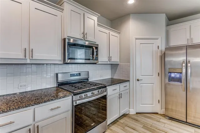 a kitchen with granite countertop a sink stove and refrigerator