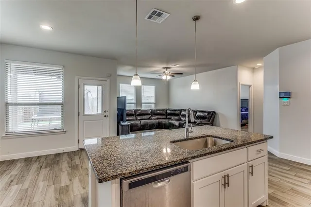 a kitchen with stainless steel appliances granite countertop a sink a oven and a granite counter tops with white cabinets