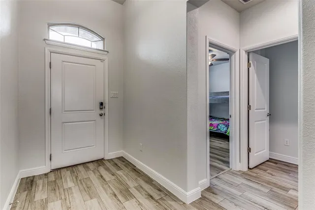 an empty room with wooden floor closet and windows