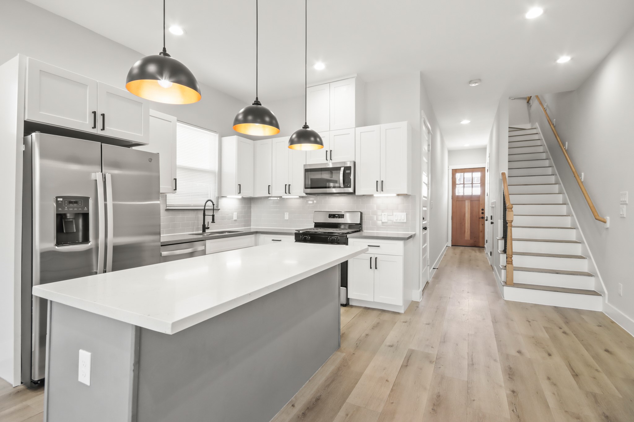 a large kitchen with kitchen island a stove a sink a center island and wooden floor