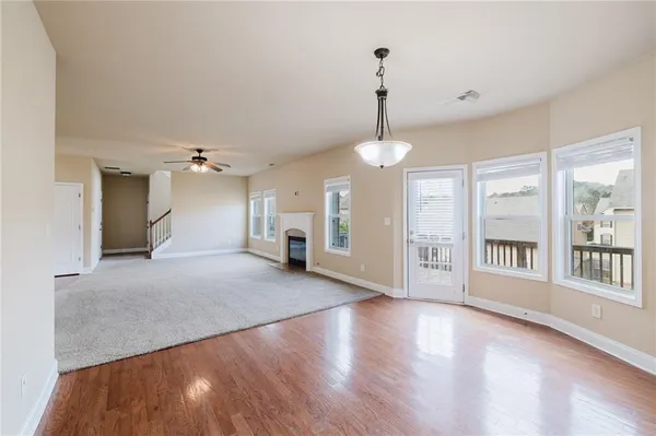 a view of an empty room with window and wooden floor