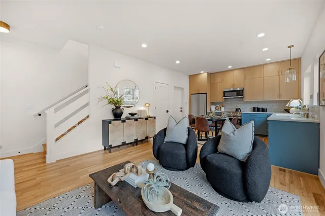 a living room with furniture kitchen view and a wooden floor