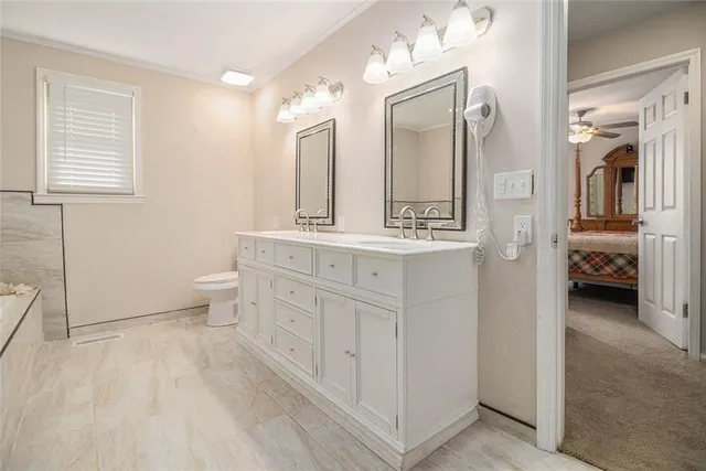 a spacious bathroom with a double vanity sink toilet and mirror