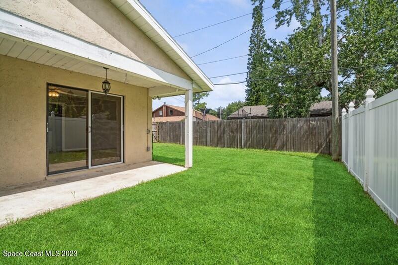 2418 Delys Street Cocoa, FL 32926 - Photo 12 of 12 a view of a backyard with large trees and wooden fence