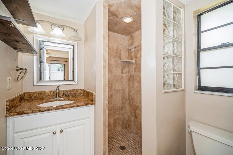 2418 Delys Street Cocoa, FL 32926 - Photo 9 of 12 a bathroom with a granite countertop sink a mirror a shower and a window