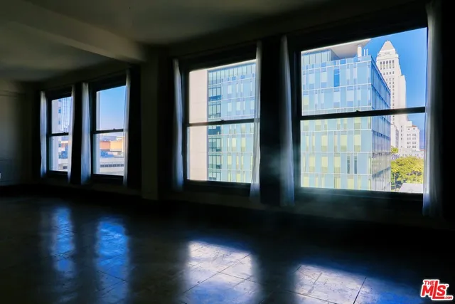 a view of an empty room with wooden floor and windows