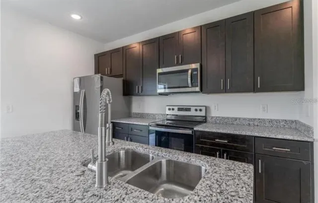 a kitchen with granite countertop a refrigerator and a sink