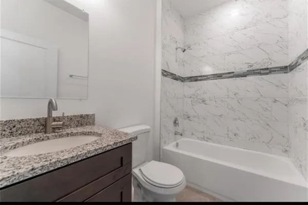 a bathroom with a granite countertop sink toilet and shower
