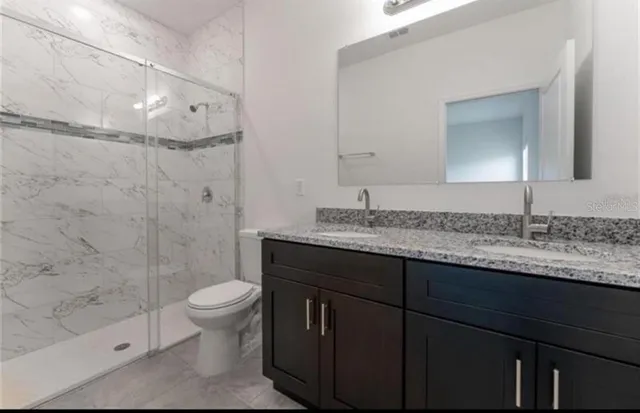 a bathroom with a granite countertop sink toilet and shower
