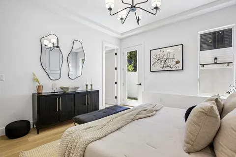 a bedroom with a bed dresser and wooden floor