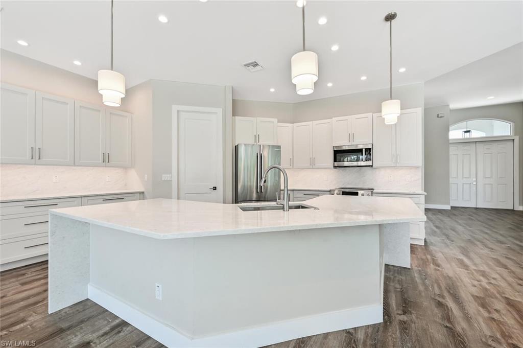4231 Crayton Road Naples, FL 34103 - Photo 11 of 46 a large kitchen with kitchen island white cabinets and white appliances
