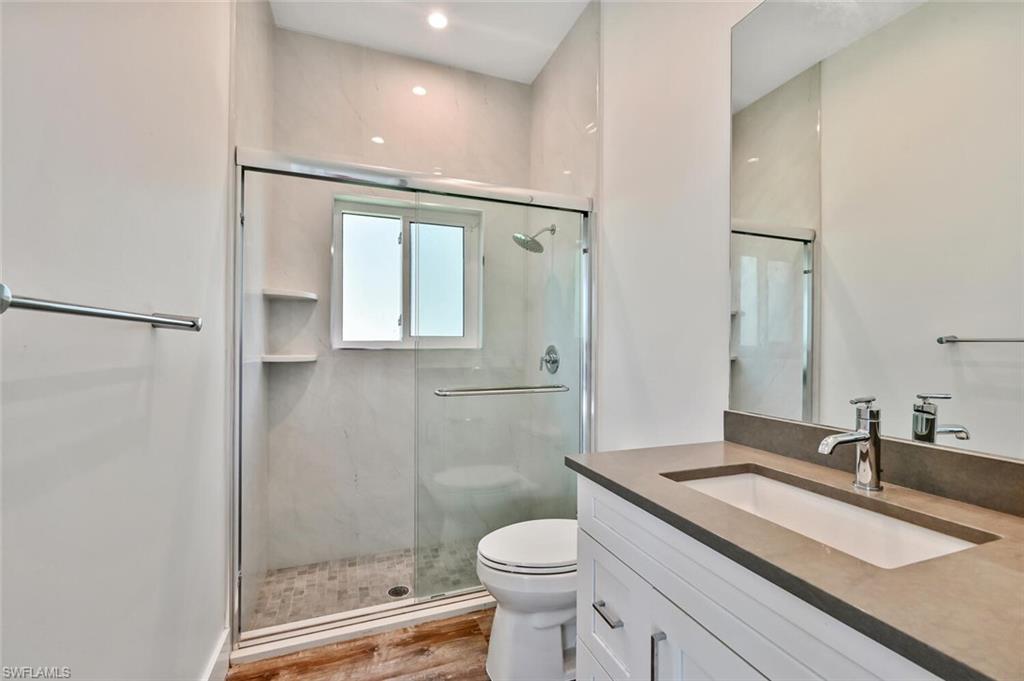 4231 Crayton Road Naples, FL 34103 - Photo 30 of 46 a bathroom with a granite countertop sink toilet and shower