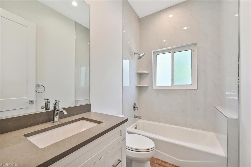 4231 Crayton Road Naples, FL 34103 - Photo 32 of 46 a bathroom with a granite countertop sink a toilet and shower
