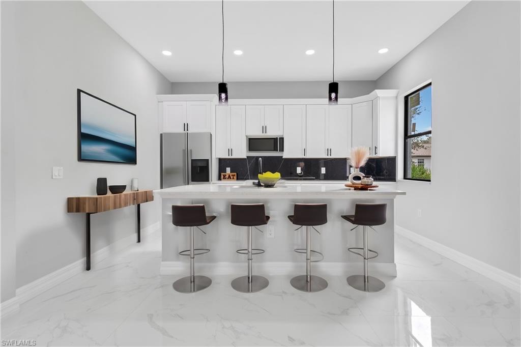 a kitchen with stainless steel appliances kitchen island granite countertop a sink and a white cabinets