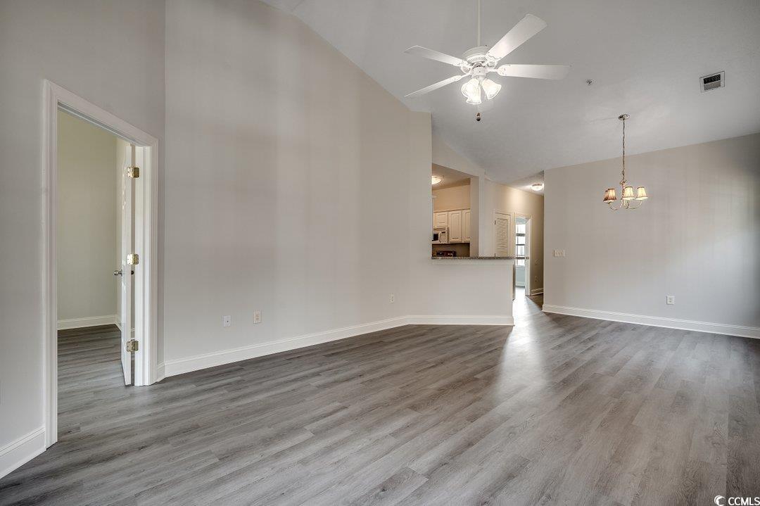 999 Algonquin Drive, Unit E Pawleys Island, SC 29585 - Photo 14 of 37 Unfurnished living room featuring visible vents, wood finished floors, high vaulted ceiling, baseboards, and ceiling fan with notable chandelier