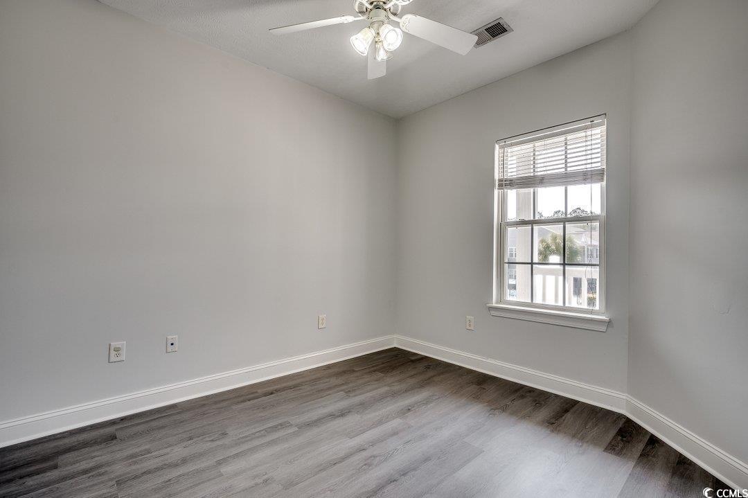 999 Algonquin Drive, Unit E Pawleys Island, SC 29585 - Photo 15 of 37 Empty room with dark wood-style floors, visible vents, baseboards, and a ceiling fan