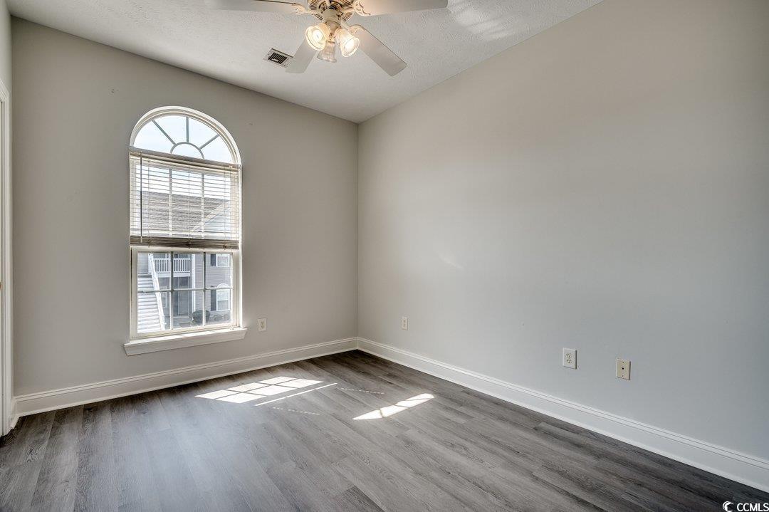 999 Algonquin Drive, Unit E Pawleys Island, SC 29585 - Photo 17 of 37 Spare room featuring ceiling fan, dark wood finished floors, visible vents, and baseboards