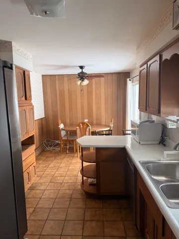 a kitchen with kitchen island granite countertop a sink refrigerator and cabinets