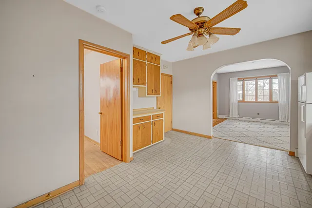 an empty room with chandelier fan and windows