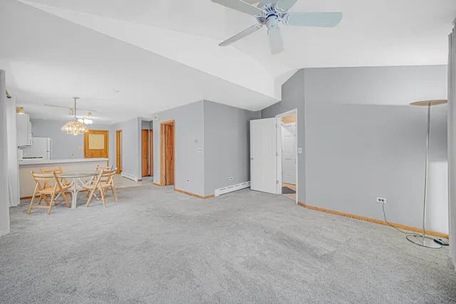 an empty room with chandelier fan and windows