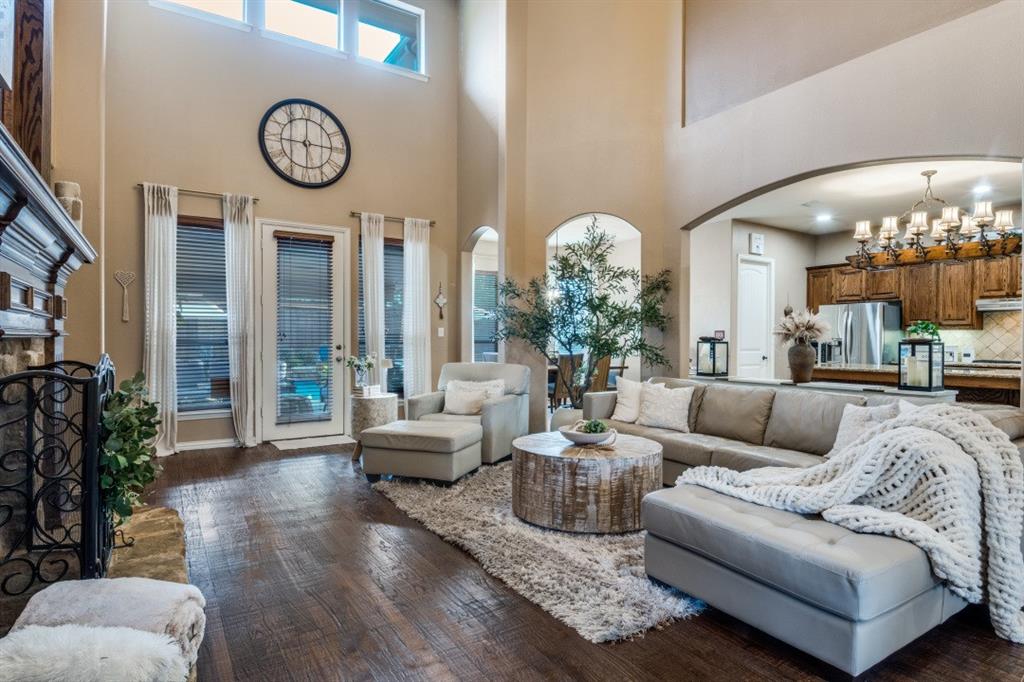 2810 Baker Street Sachse, TX 75048 - Photo 4 of 26 Living area with a chandelier, arched walkways, a fireplace with raised hearth, dark wood finished floors, and a towering ceiling