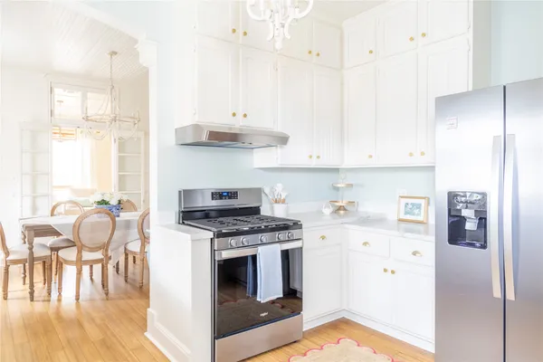 a kitchen with stainless steel appliances granite countertop a stove a refrigerator and a dining table with wooden floor