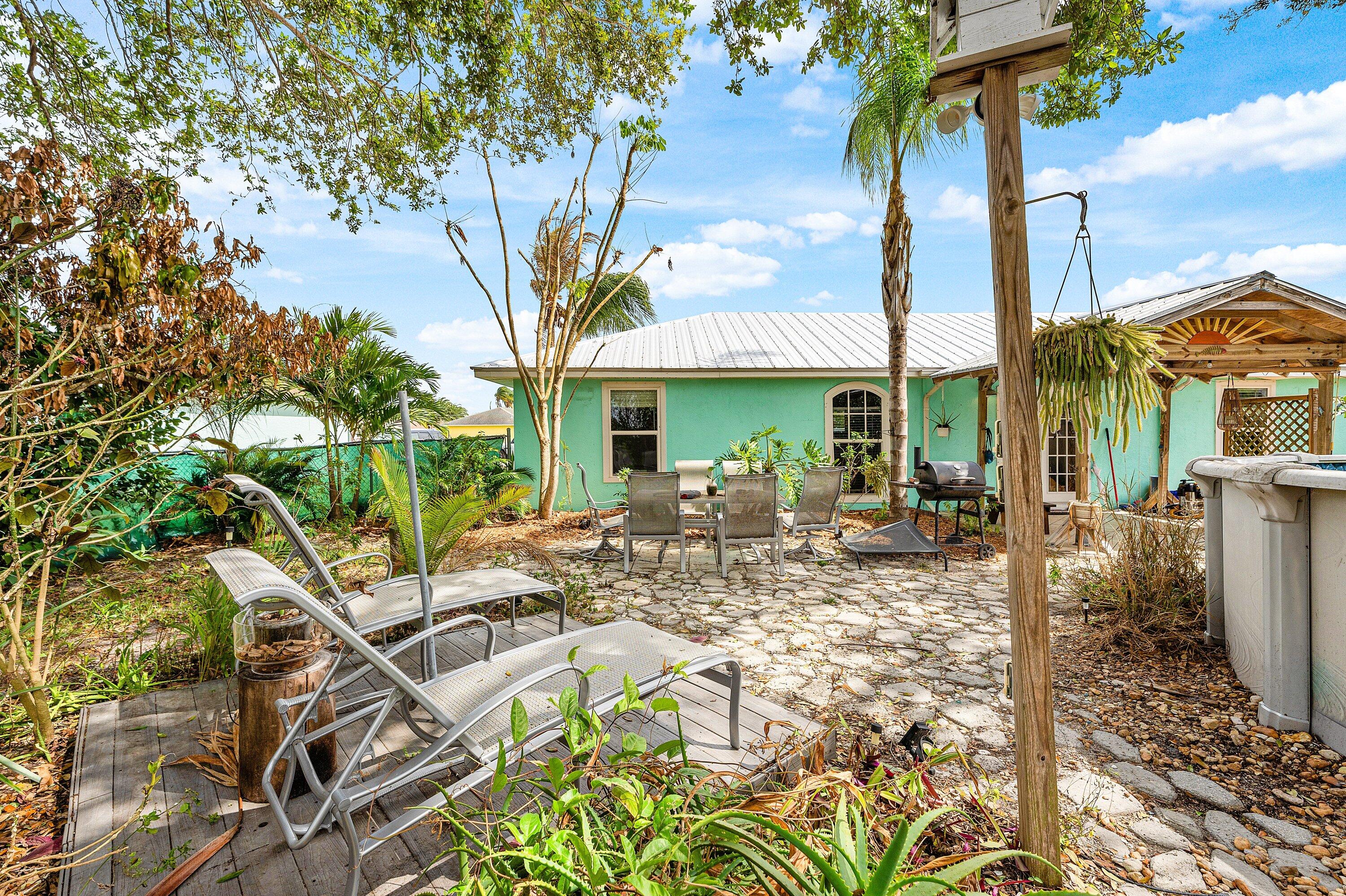 2114 Southeast Midtown Road Port St. Lucie, FL 34952 - Photo 26 of 41 a view of a patio with table and chairs potted plants and palm trees