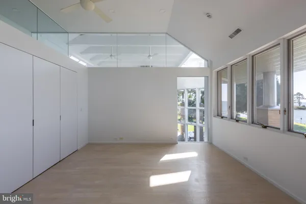 a view of empty room with wooden floor and fan
